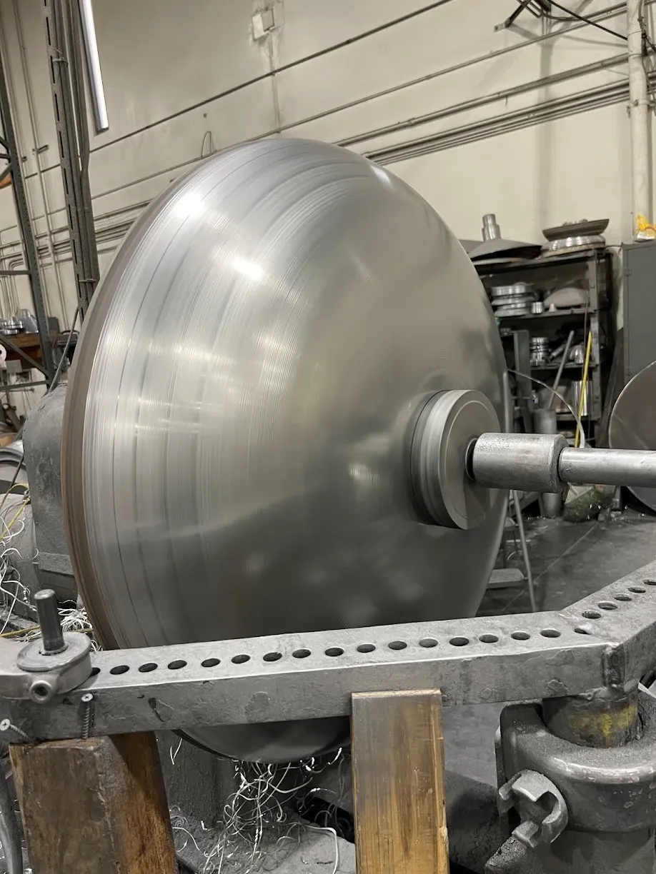 A large aluminum disc spinning on the lathe during forming