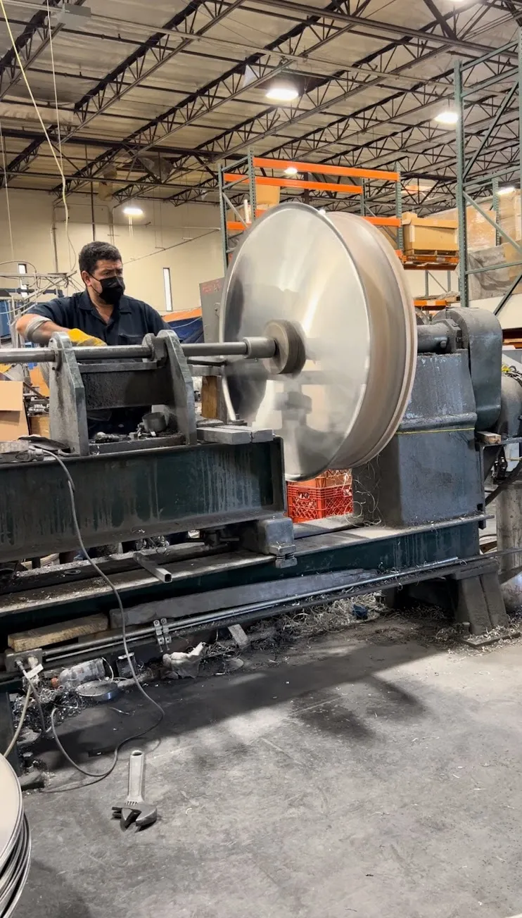Raul Rizo hand spinning a large aluminum part on a spinning lathe in the SRJ shop